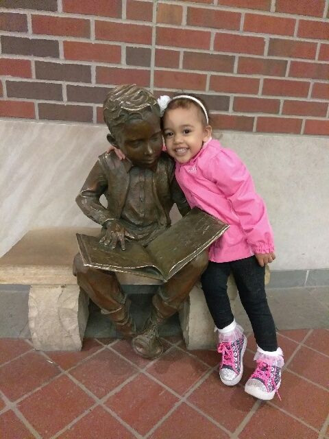 kid sitting beside a statue
