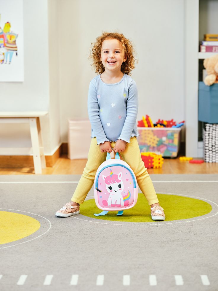 a kid checking the weight of her backpack as a way of choosing the right backpack for kids