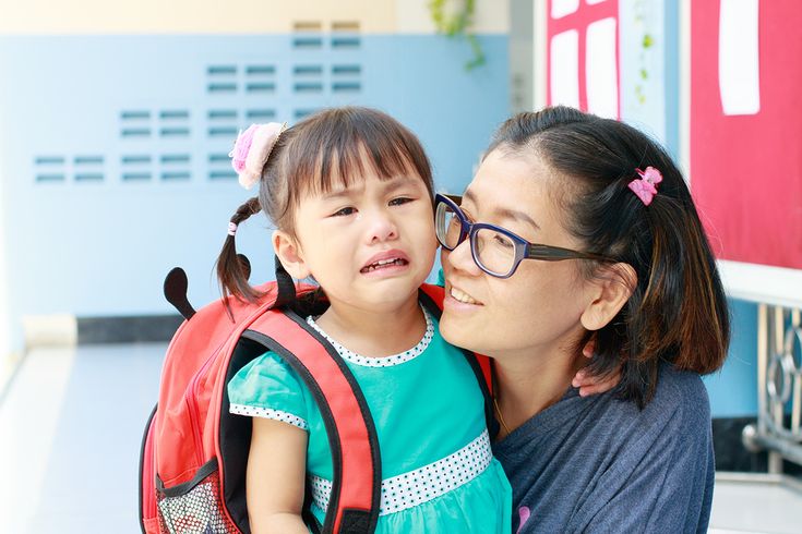 mom helping her crying kid with her first day in school anxiety