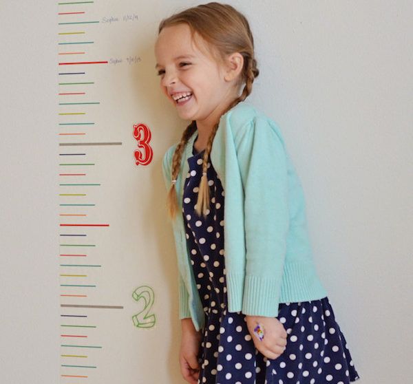 kid taking picture besides growth chart as first day of school photo idea
