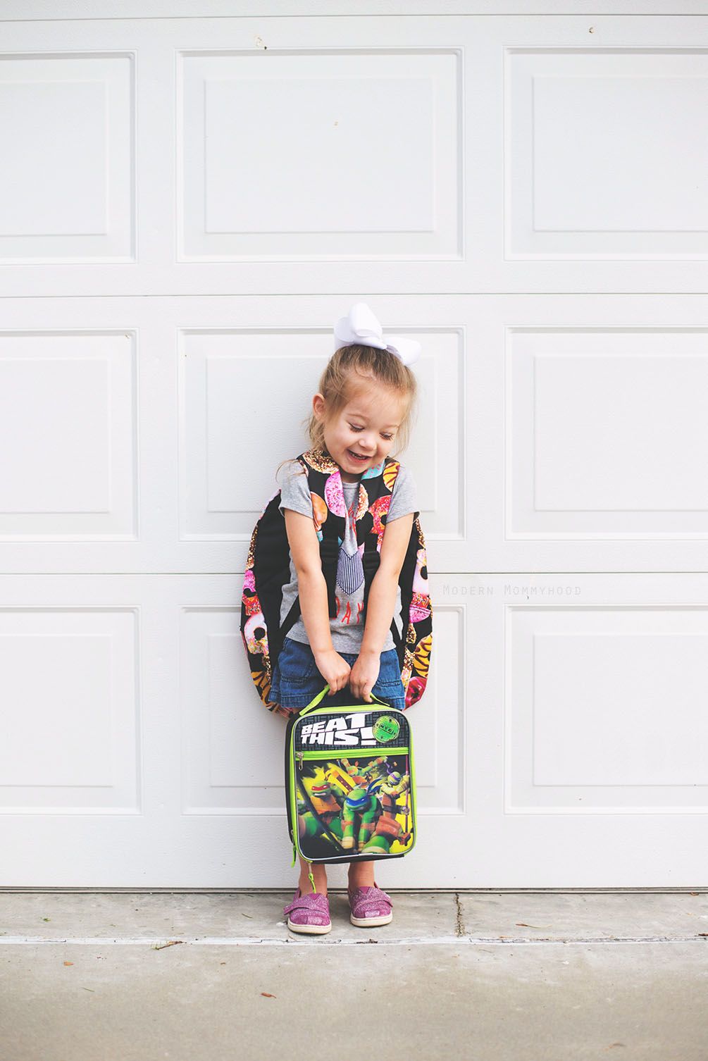 kid taking picture with her backpack and lunch box as first day of school photo idea