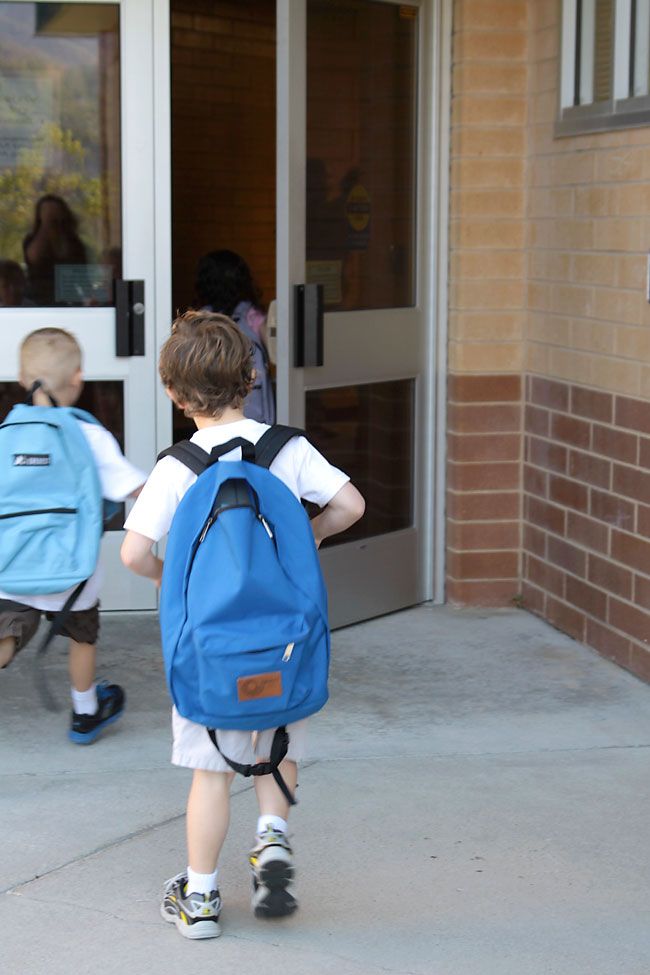 kid walking inside his classroom with his backpack
