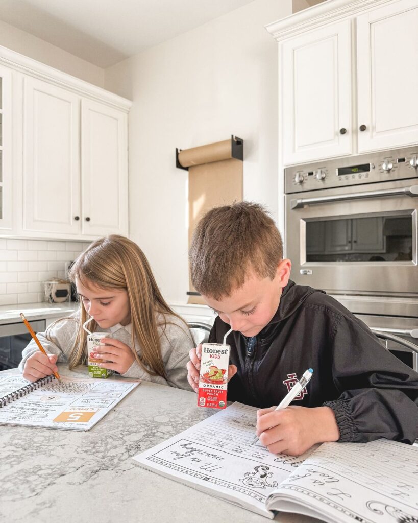 kids doing their homework as they snack on juice