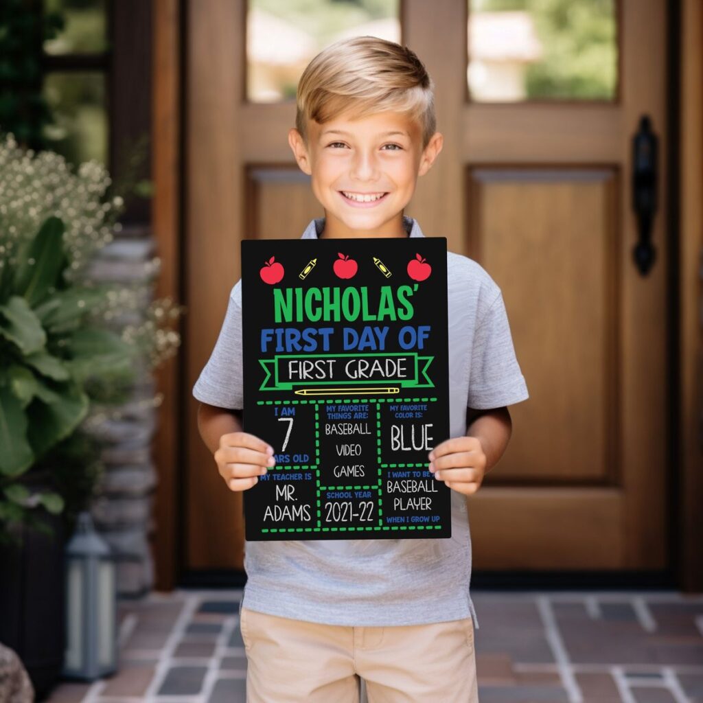 school kid taking picture with a small chalkboard sign with his details written on it