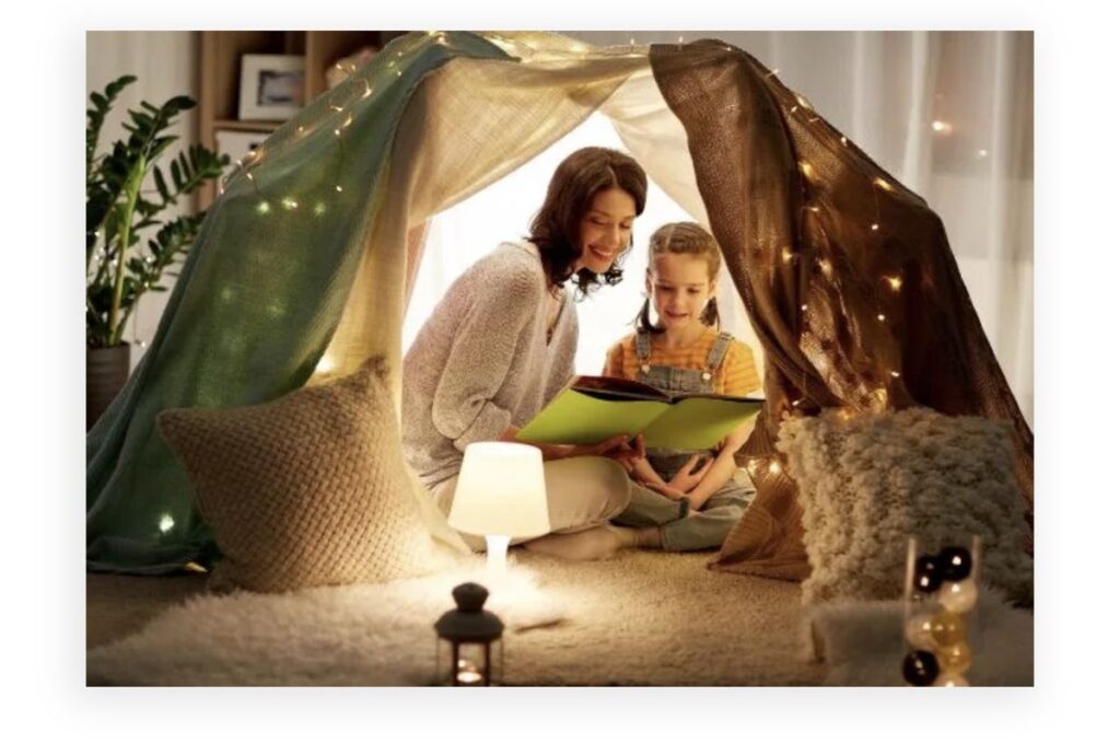 mom and kid reading inside a blanket fort