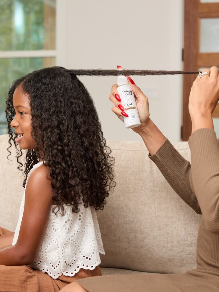 mom applying curly hair spray on her kid's hair
