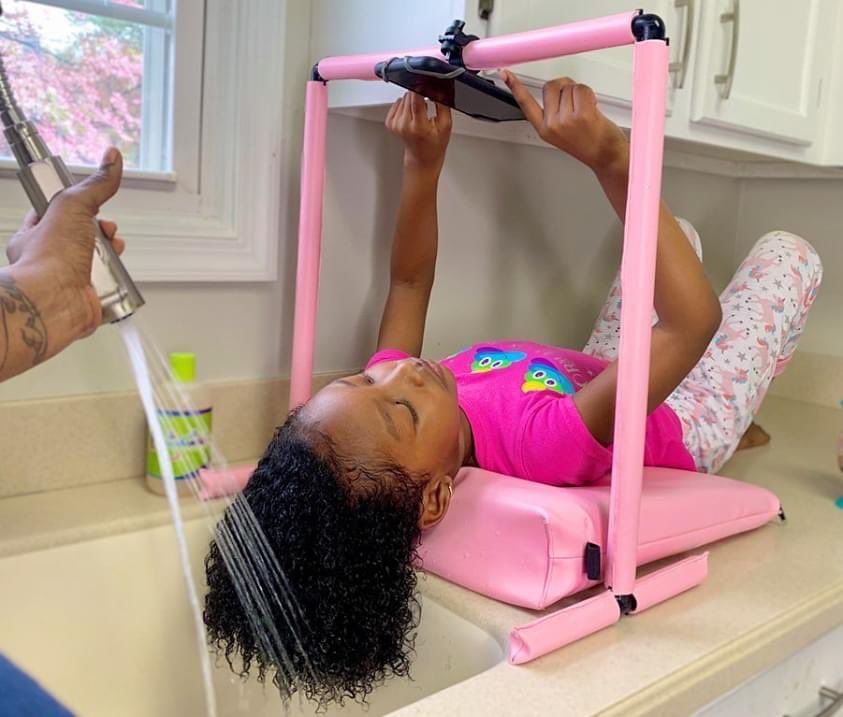 kid watching movie while washing her hair