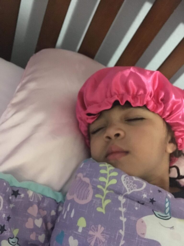 kid with silk bonnet sleeping on a silk pillowcase as one of the way to protect kid's hair while they sleep