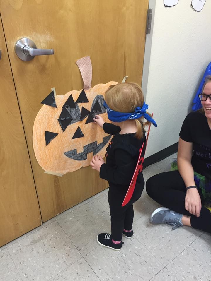 kid playing pin the nose on the pumpkin game