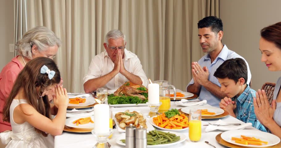 family praying before eating as part of the way to raise grateful kids