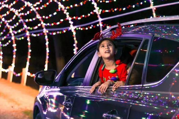 family driving through christmas lights as the kids watches from the window as Christmas activities that create magical family memories