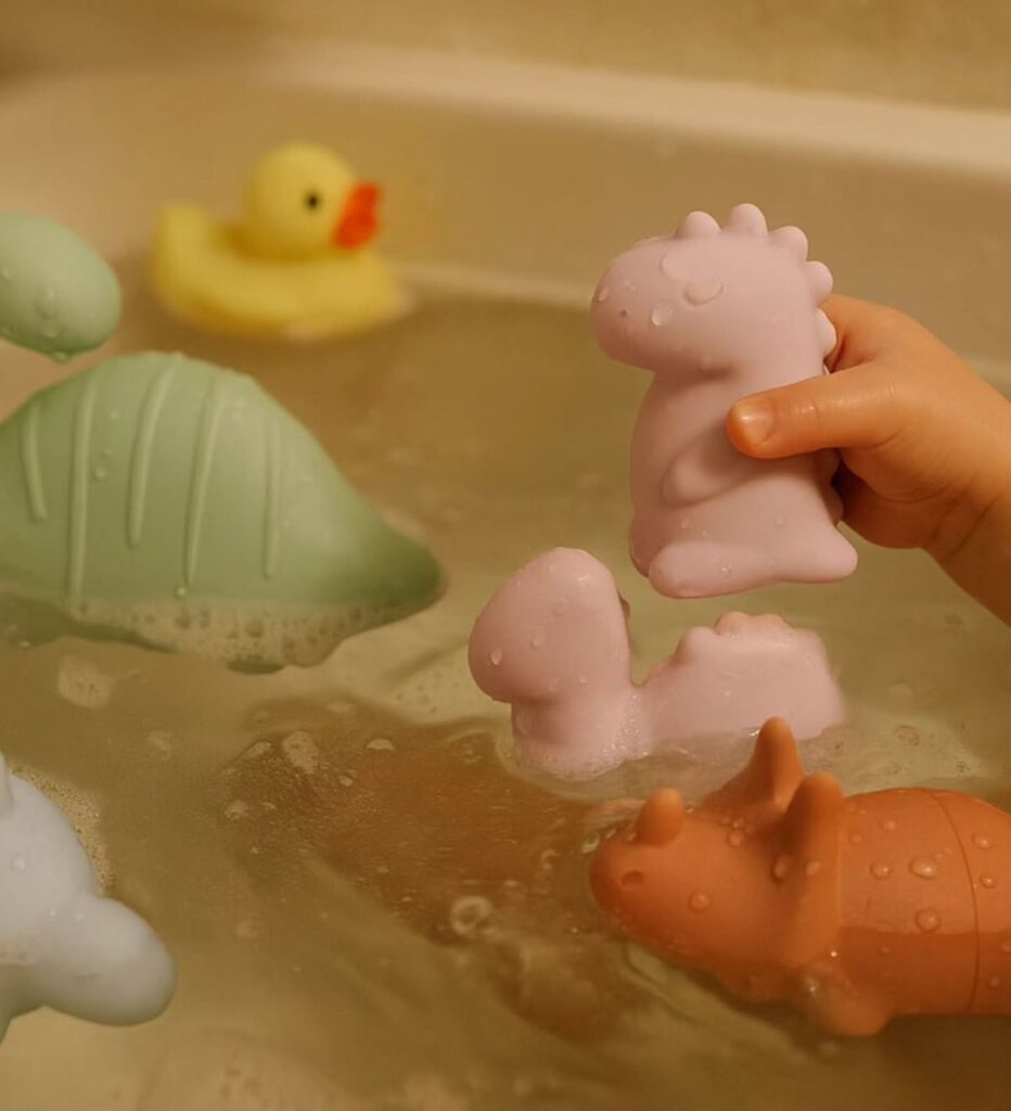 a kid rescuing toy dinosaurs from a bath as water play activities for toddlers