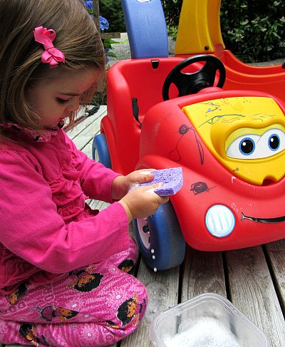 toddler washing her toy car