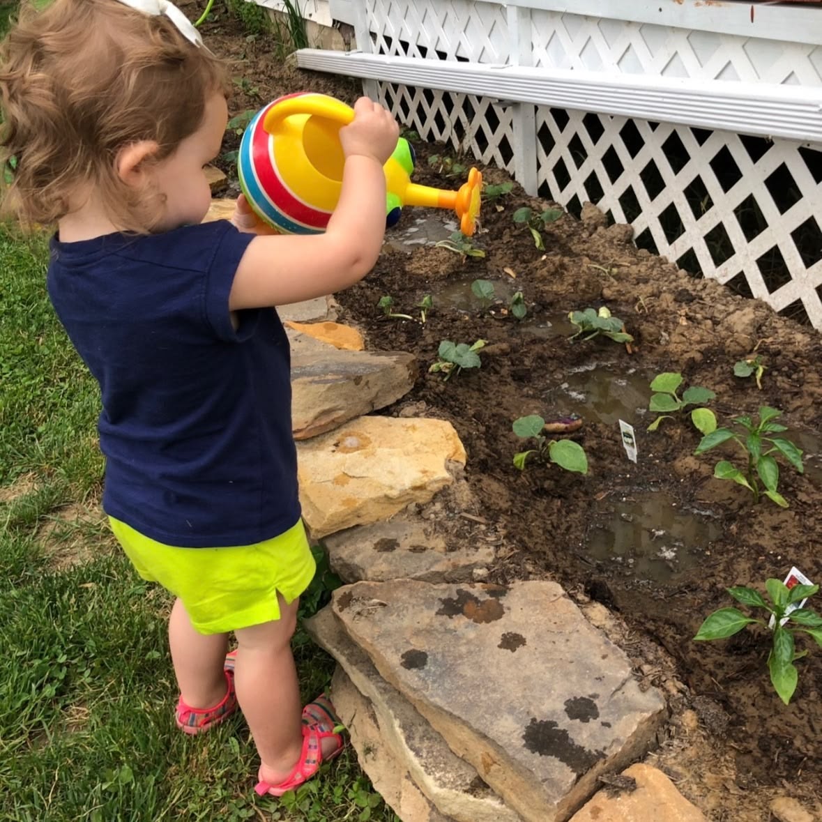 toddler watering the garden plants as water play activities for toddlers