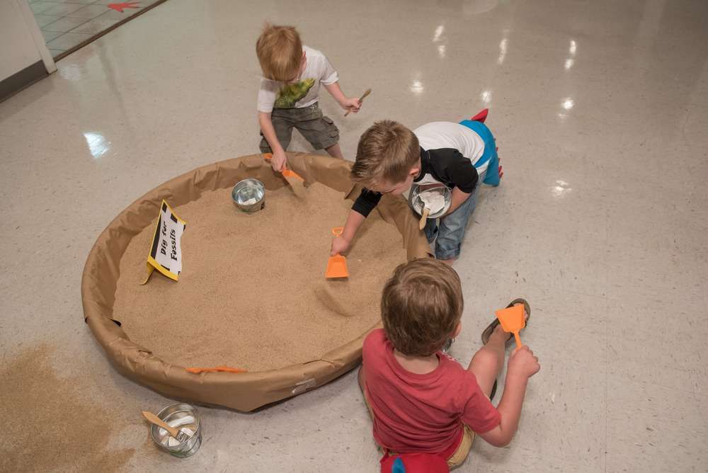kids digging a bowl of sand in search of dinosaur
